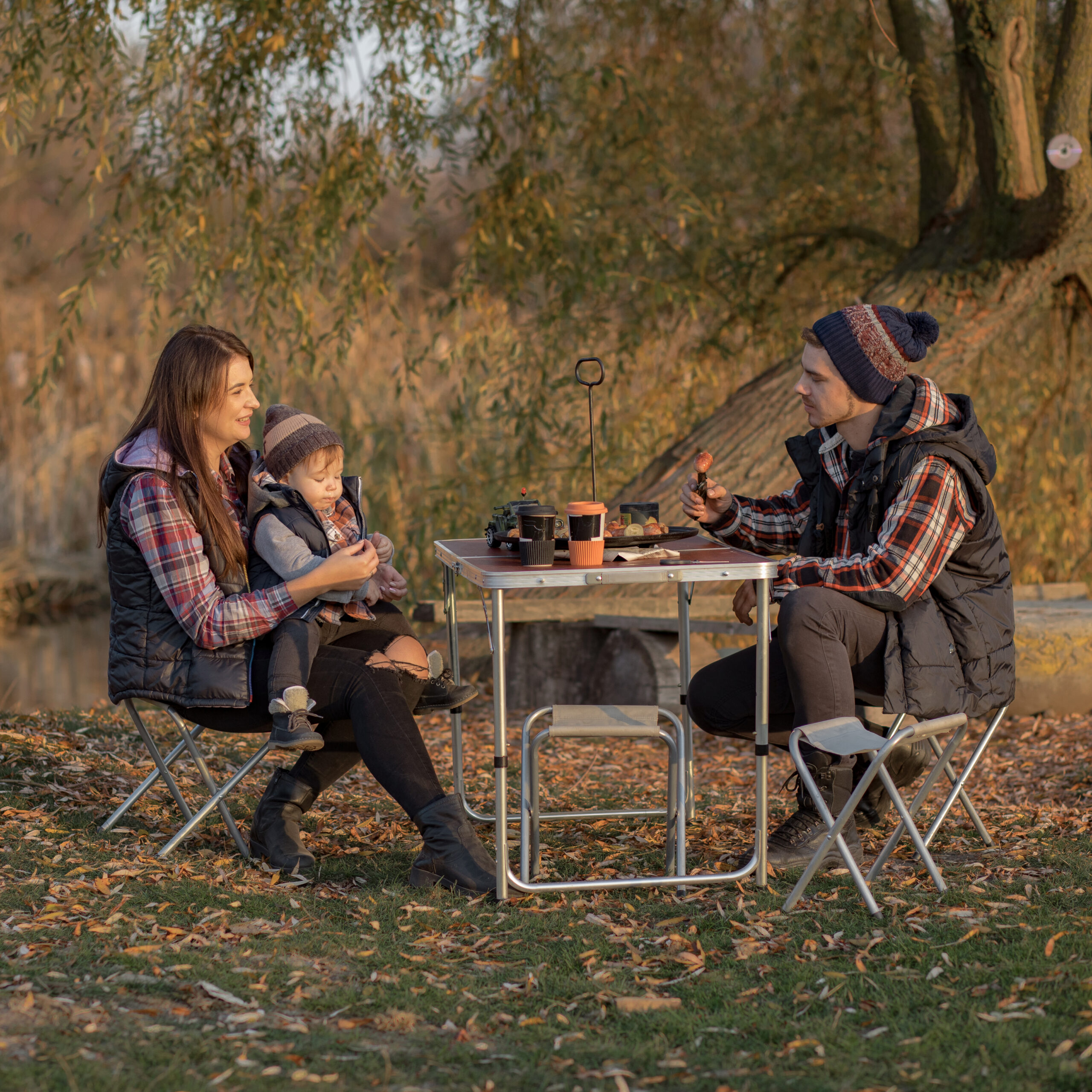 Family with cute little son. Man with son eatting meat. People on a picnick.